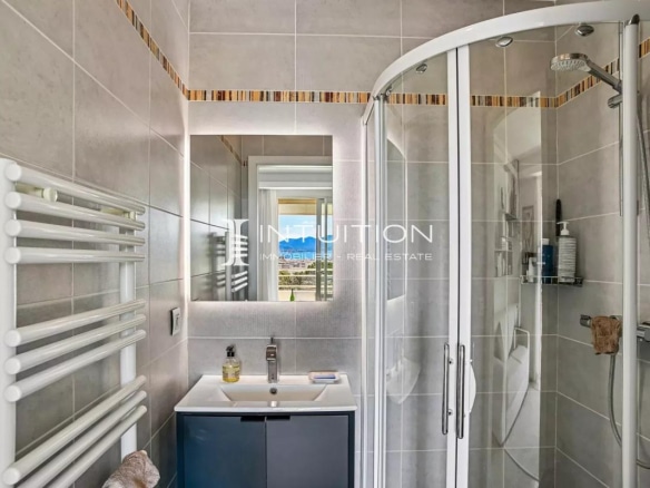 Modern bathroom with shower, light tiles and mirror, view of the outside.