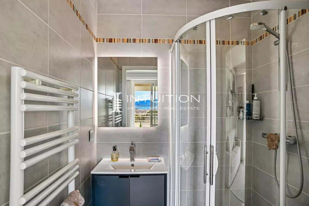 Modern bathroom with shower, light tiles and mirror, view of the outside.
