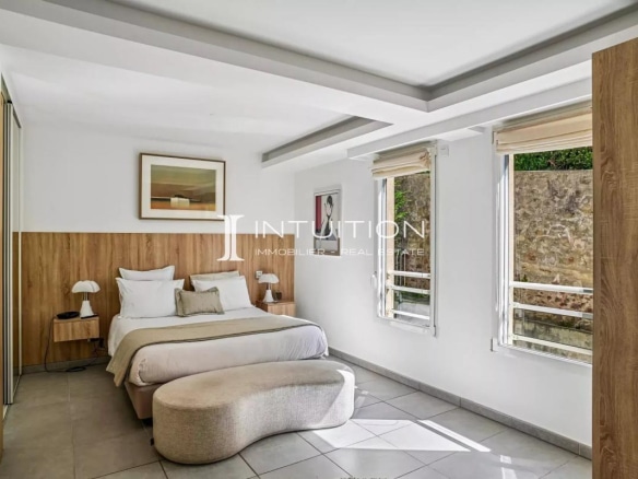 Modern apartment room with double bed and bright windows.