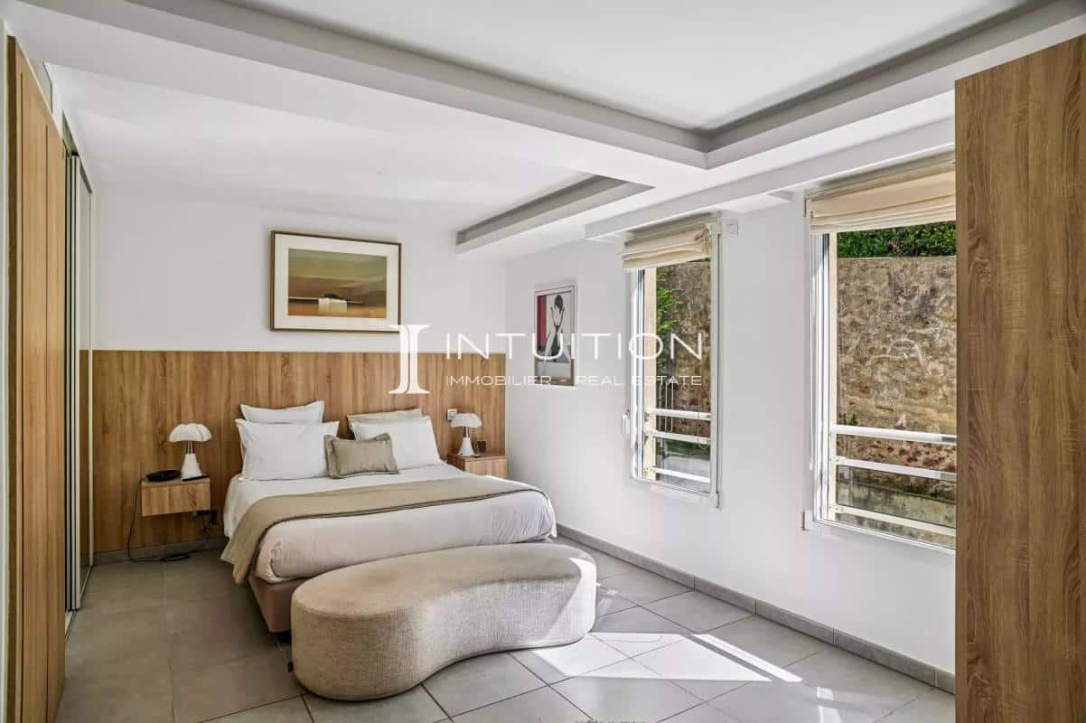 Modern apartment room with double bed and bright windows.