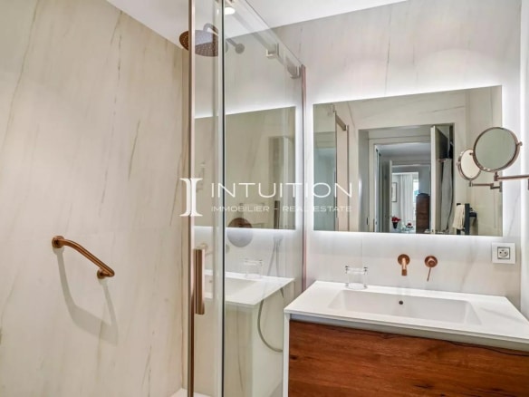 Modern bathroom with glass shower and wooden vanity.