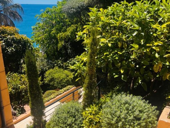 Escaliers menant à un jardin verdoyant avec vue sur la mer Méditerranée.