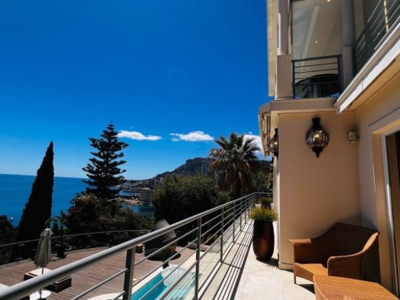 Vue de la terrasse d'une villa contemporaine à Roquebrune-Cap-Martin, avec piscine et mer en arrière-plan.