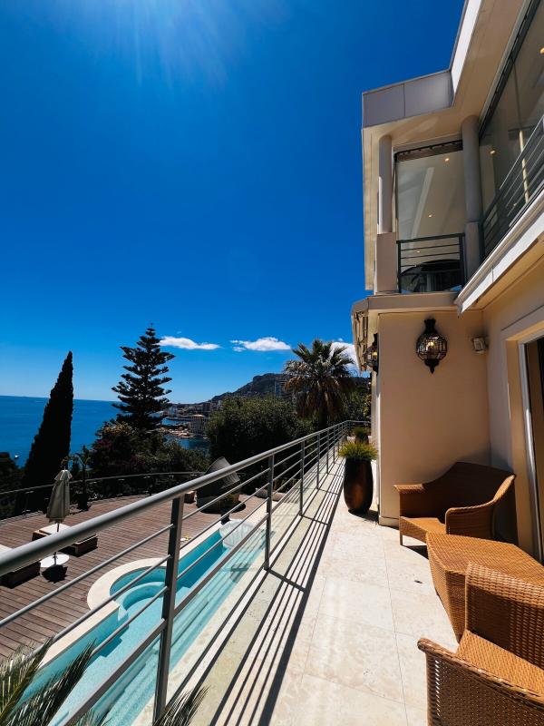 Vue de la terrasse d'une villa contemporaine à Roquebrune-Cap-Martin, avec piscine et mer en arrière-plan.