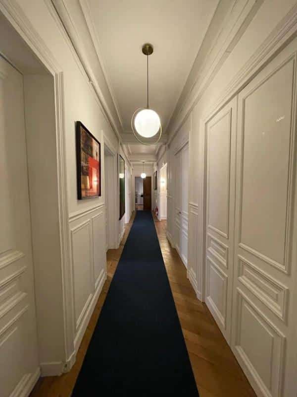 Couloir d'un appartement à Paris avec parquet et moulures, éclairage moderne