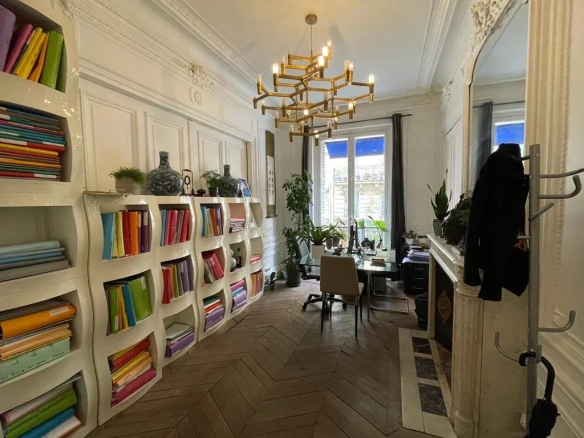 Intérieur d'un appartement à rénover avec bibliothèque colorée et bureau, Paris 8ème.