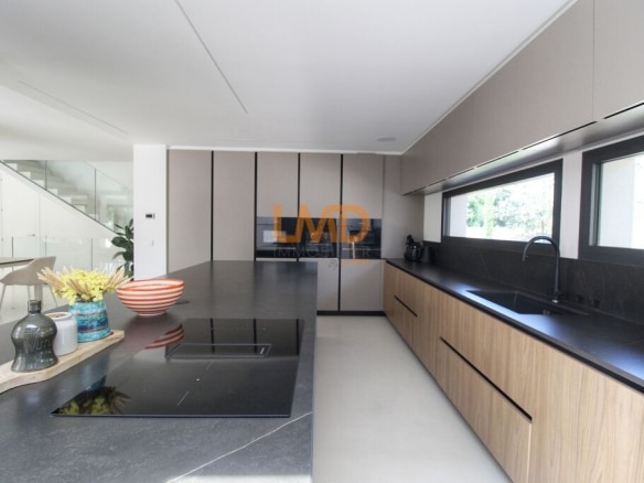 Cuisine moderne d'une villa contemporaine avec plans de travail en noir et bois, fenêtres lumineuses.