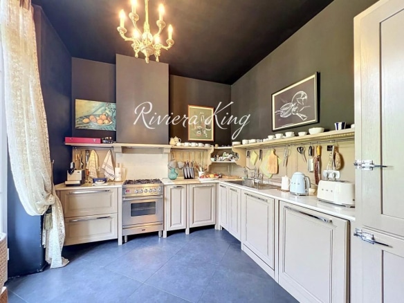 Cuisine d'un appartement de style Belle Époque avec des éléments modernes, murs sombres et équipements de qualité.