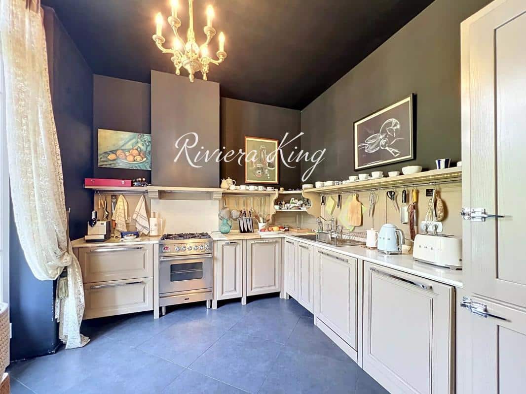 Cuisine d'un appartement de style Belle Époque avec des éléments modernes, murs sombres et équipements de qualité.