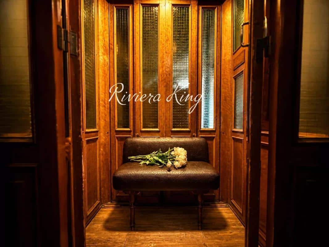 Intérieur d'un hall d'entrée en bois avec un banc et des fleurs, style Belle Époque.