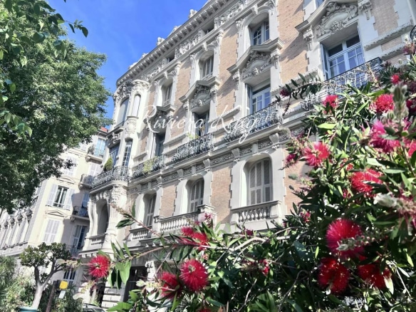 Façade du Palais Meyerbeer sur le boulevard Victor Hugo à Nice, avec des fleurs au premier plan.