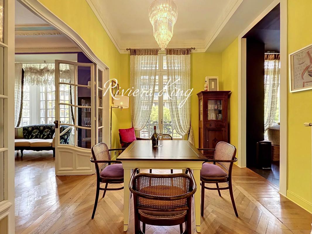 Intérieur d'un appartement de style Belle Époque avec un salon lumineux et une salle à manger.