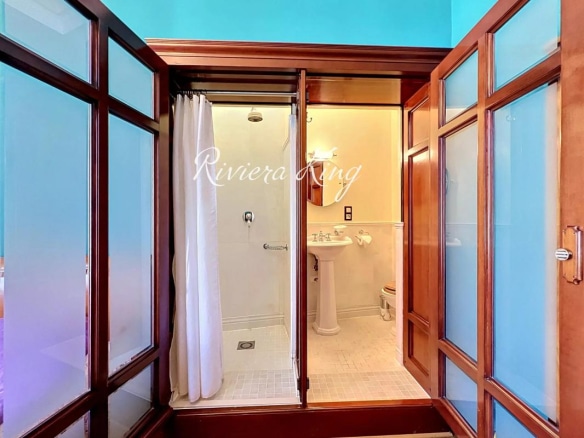 Salle de bain d'un appartement Belle Époque avec douche et éléments en bois au Palais Meyerbeer à Nice.