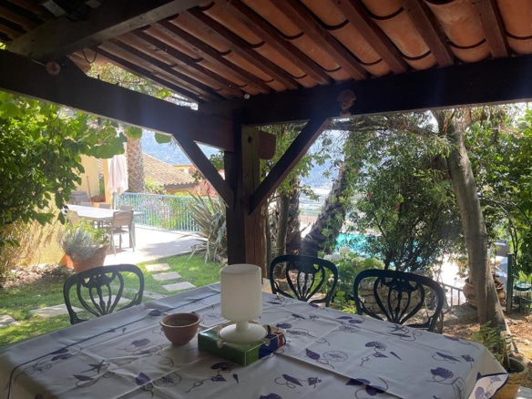 Terrasse ombragée avec table et chaises, vue sur la piscine et le jardin à Gattières.