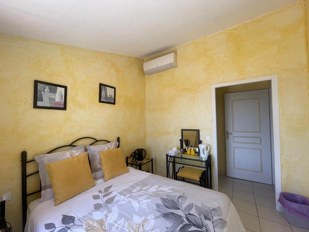 Chambre d'une maison à Gattières avec murs jaunes, lit double et décoration simple.