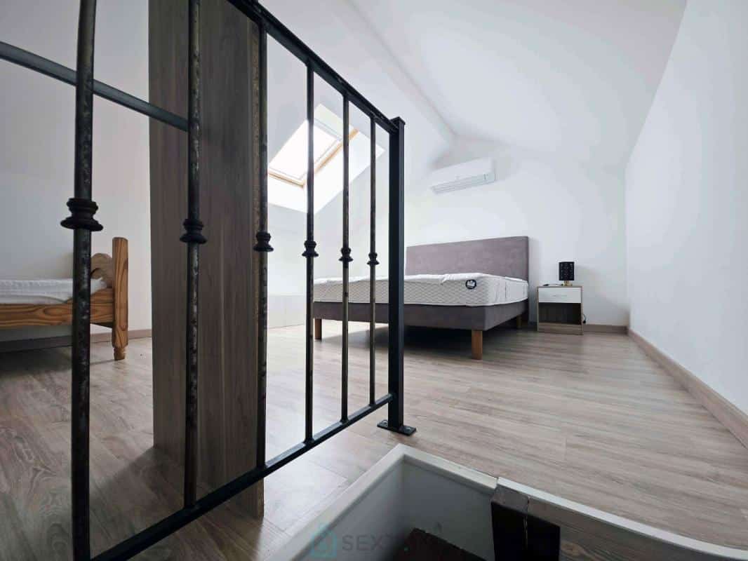 Spacious room with beds and natural light, overlooking a staircase