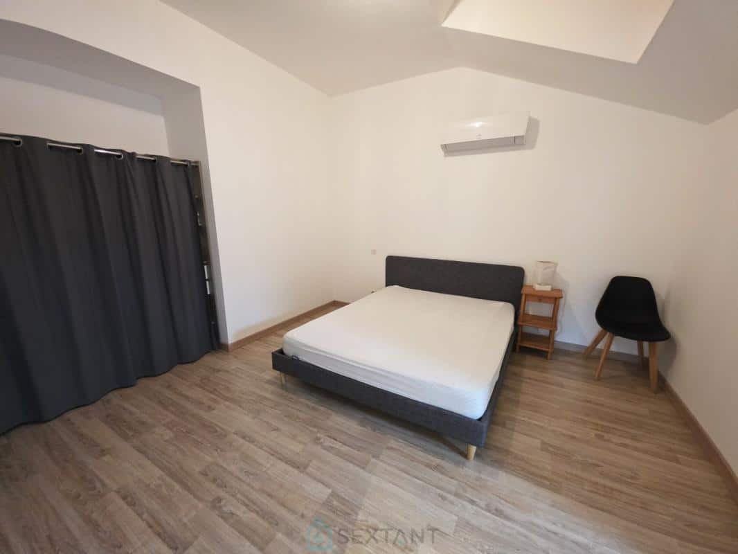 Empty room with a single bed, a chair and a grey curtain.