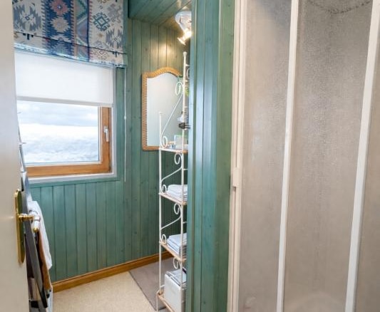 Intérieur d'un triplex au Thuya à Avoriaz, montrant un couloir avec douche et étagères.