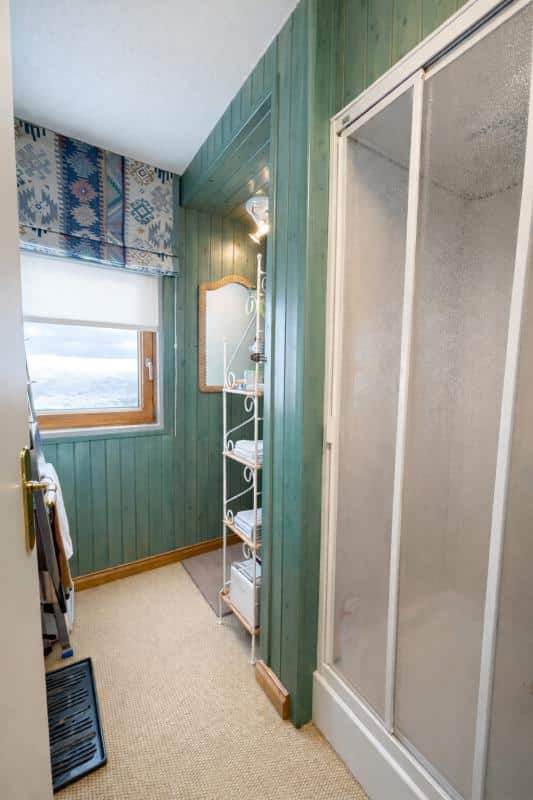 Intérieur d'un triplex au Thuya à Avoriaz, montrant un couloir avec douche et étagères.