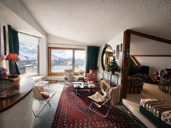Salon lumineux d'un triplex avec vue sur la vallée, décoré avec des fauteuils et un tapis.