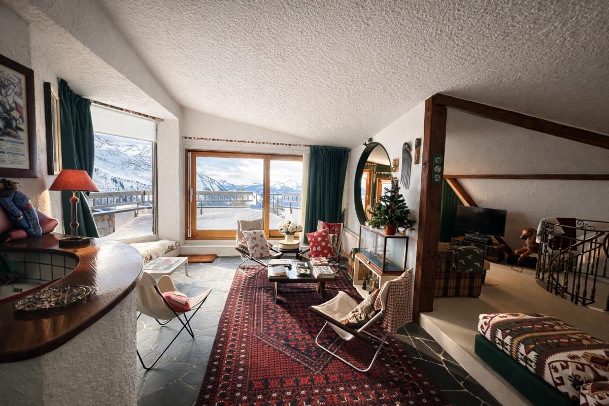 Salon lumineux d'un triplex avec vue sur la vallée, décoré avec des fauteuils et un tapis.