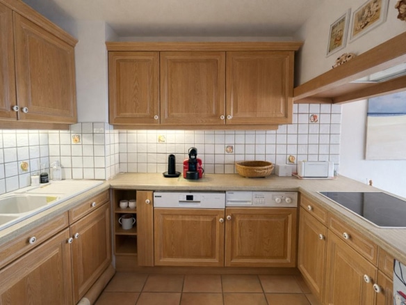 Cuisine en bois avec évier, lave-vaisselle et plaques de cuisson, dans un appartement à Avoriaz.