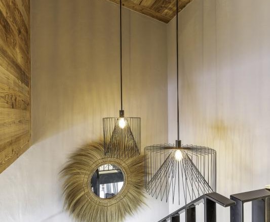 Escalier intérieur du chalet avec éclairage suspendu et miroir décoratif.