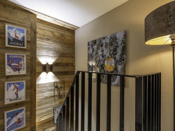 Intérieur du Chalet de la Combe à Avoriaz, montrant un escalier et des affiches de ski.