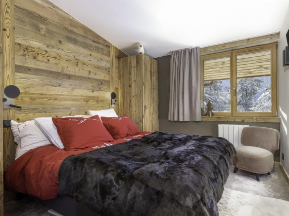 Chambre confortable avec lit double et décoration en bois, située dans un chalet à Avoriaz.