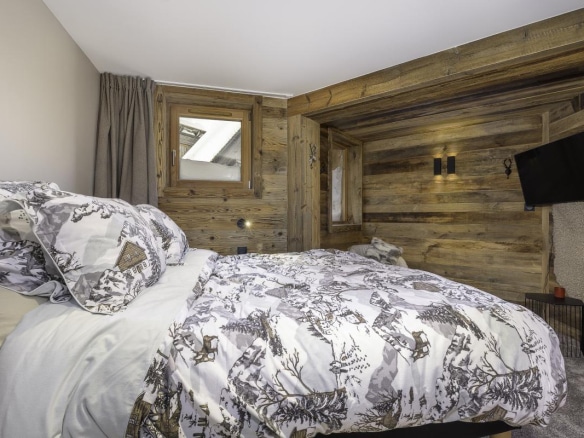 Chambre d'un chalet en bois avec un lit et des murs en bois, décorée avec des motifs de montagne.