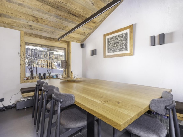 Intérieur du Chalet de la Combe à Avoriaz, avec une grande table en bois et des chaises modernes.