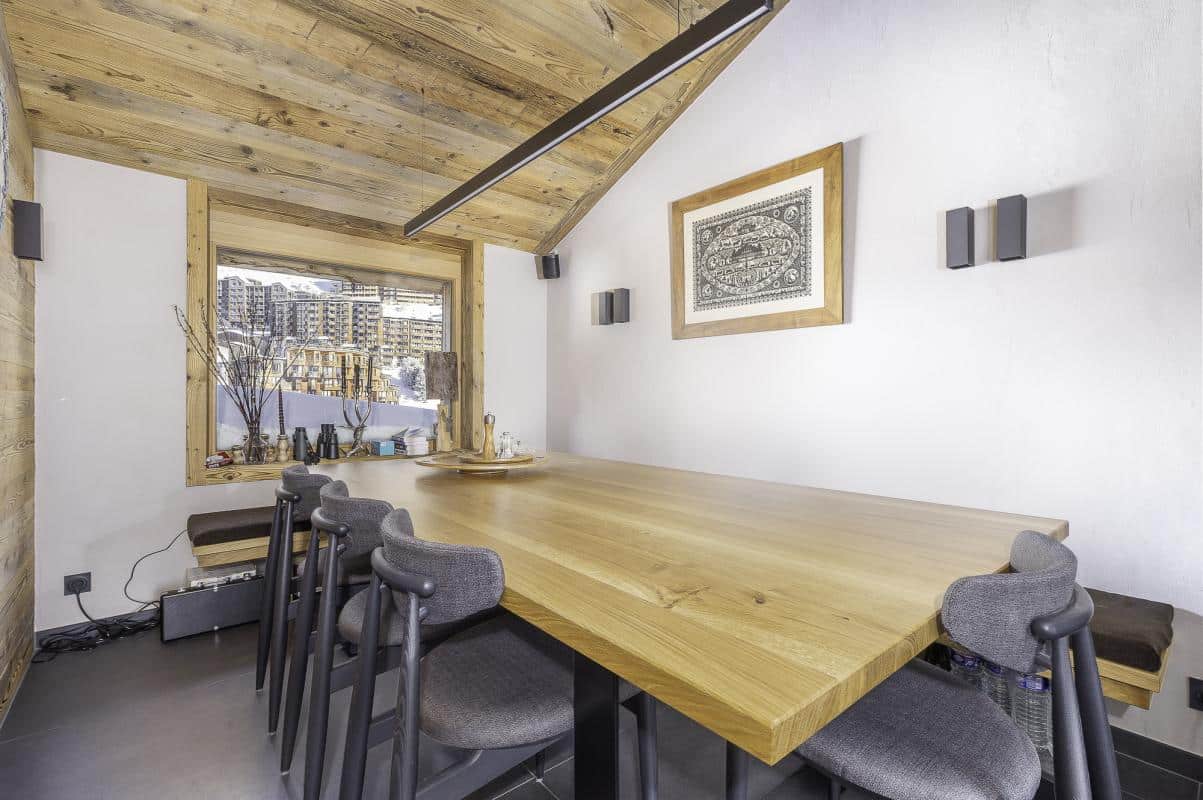 Intérieur du Chalet de la Combe à Avoriaz, avec une grande table en bois et des chaises modernes.