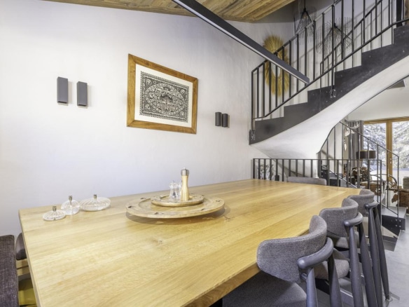 Intérieur du Chalet de la Combe à Avoriaz avec une grande table en bois et un escalier moderne.