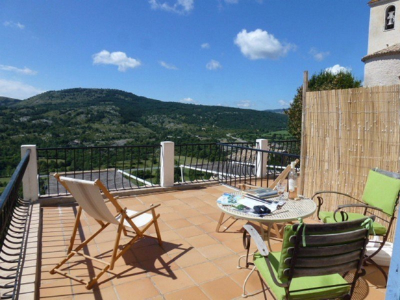 Terrasse d'une vaste demeure à Coursegoules avec vue sur les collines et la nature environnante.