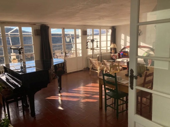 Intérieur d'une vaste demeure à Coursegoules avec un piano et une vue sur la nature.