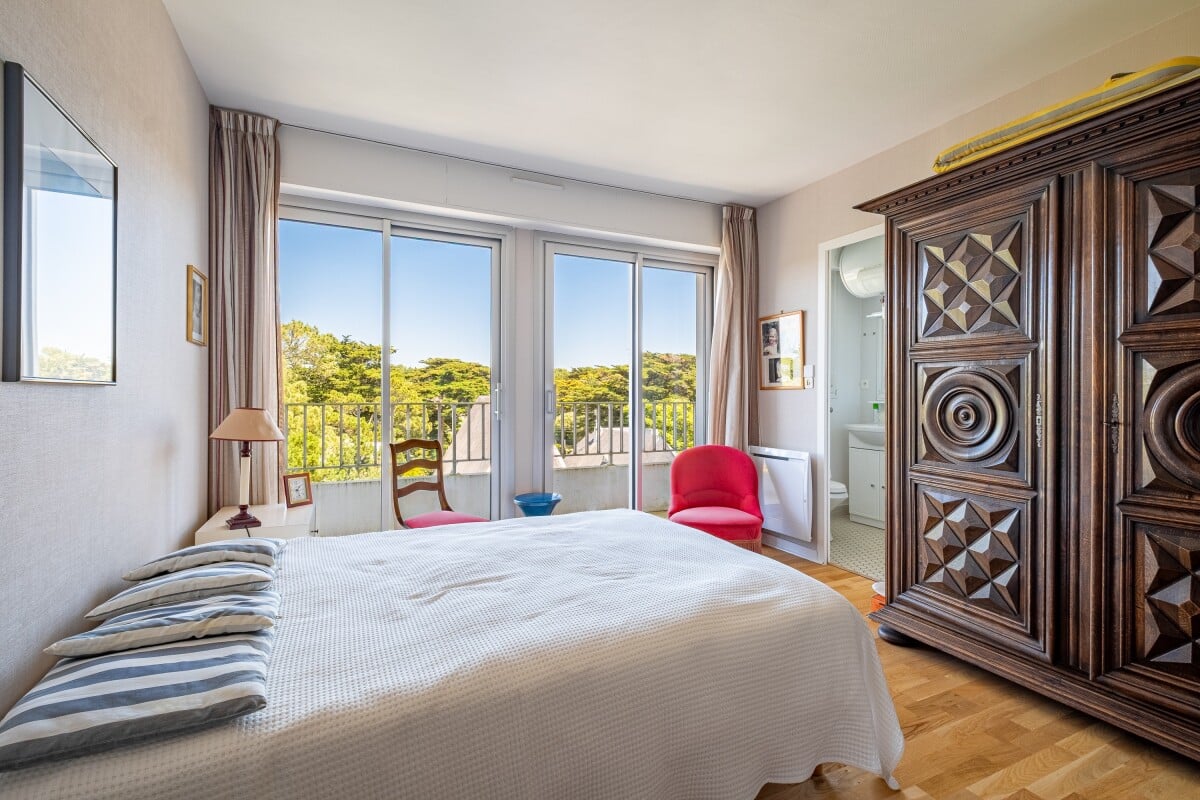 Chambre d'appartement avec lit double et fenêtres donnant sur la nature à La Baule-Escoublac.