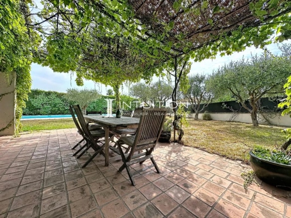 Terrace of a villa in Mougins with wooden table and view of the pool and garden.