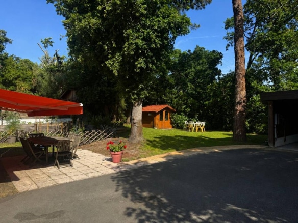 Jardin paysager d'une propriété à Arcachon avec mobilier extérieur et abri en bois.