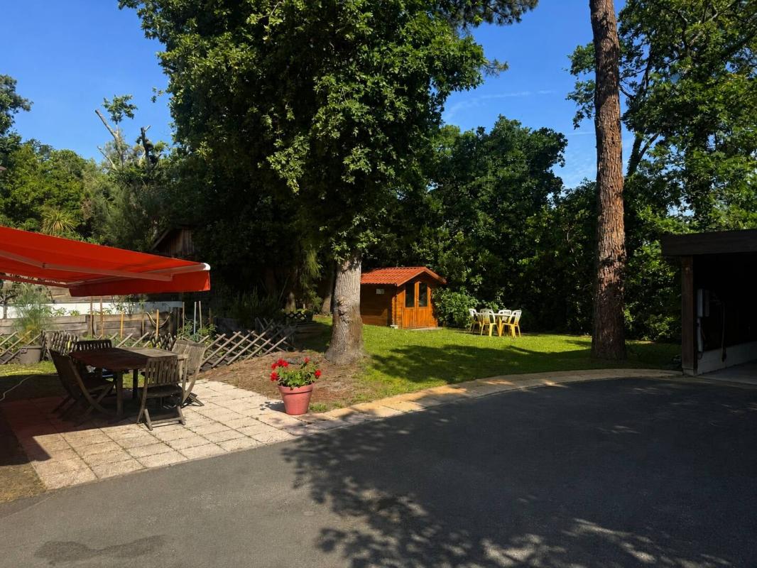 Jardin paysager d'une propriété à Arcachon avec mobilier extérieur et abri en bois.
