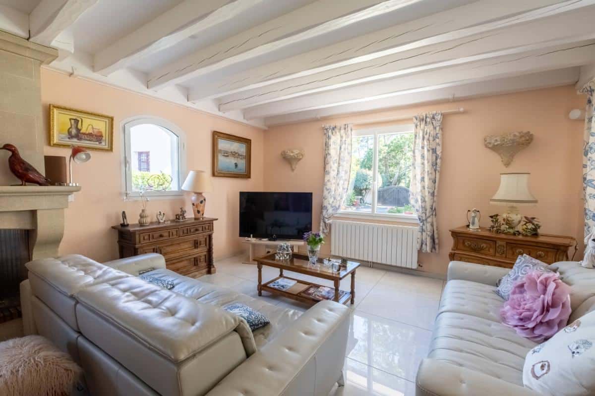 Intérieur d'un salon lumineux avec canapé en cuir, cheminée et télévision.