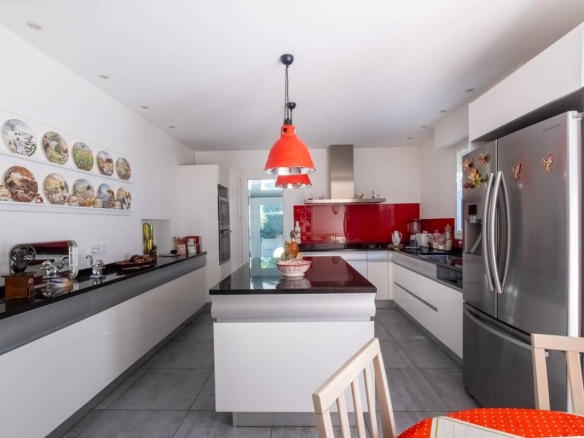 Cuisine moderne avec mobilier blanc et plan de travail en noir, éclairage rouge, dans une maison à Arcachon.
