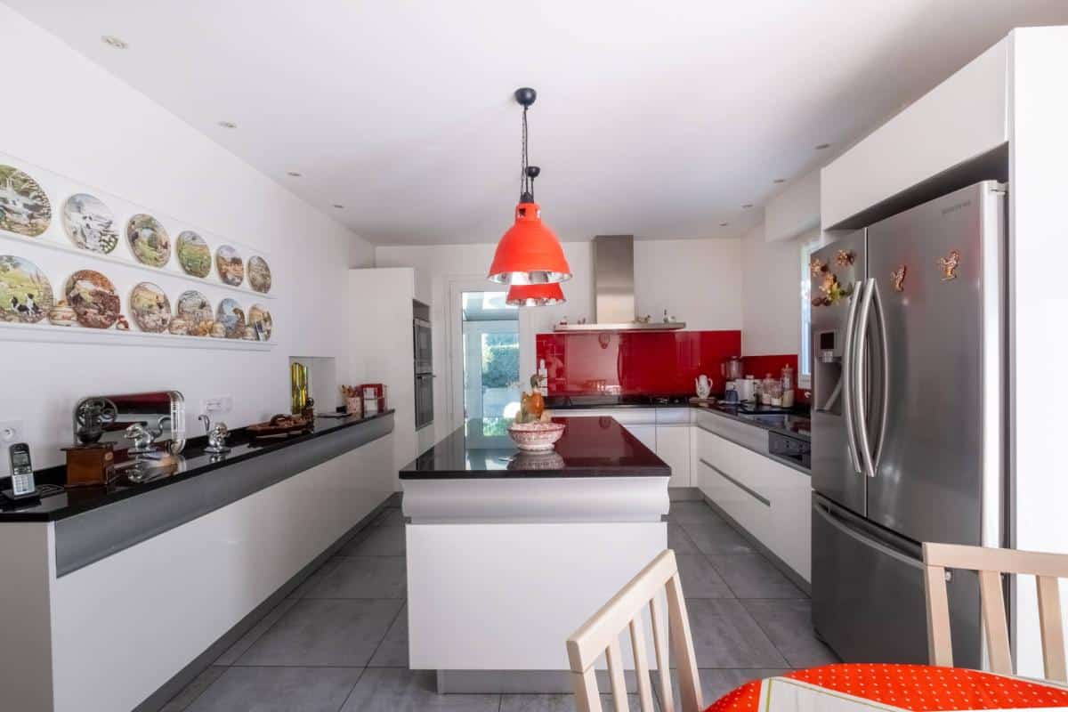 Cuisine moderne avec mobilier blanc et plan de travail en noir, éclairage rouge, dans une maison à Arcachon.