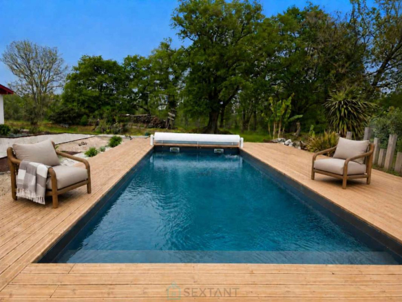 Piscine entourée de chaises en bois dans un domaine verdoyant à Saint-Jean-de-Marsacq.