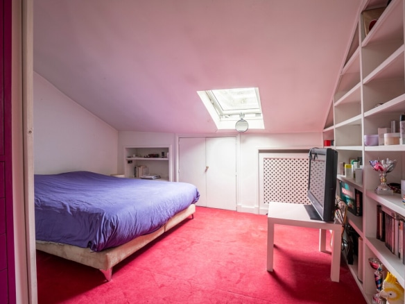 Artist's studio bedroom with a bed and a desk, natural light through a skylight.