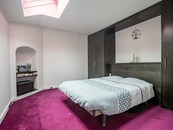 Room in an artist's studio with a double bed and pink carpet, Paris 16th arrondissement.