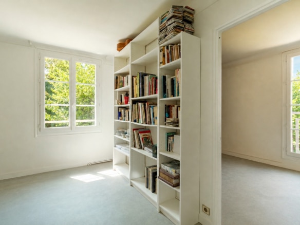 Interior of a house with shelves filled with books and windows letting in natural light.