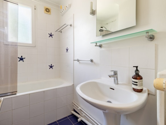 Bathroom with bathtub, sink and mirror, decorated with white and blue tiles.