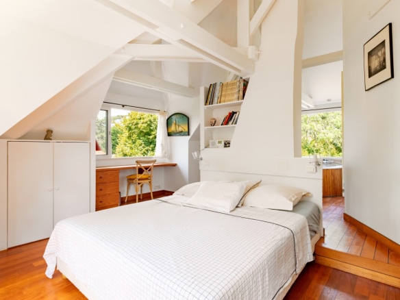 Room in a house in La Celle-Saint-Cloud with bed, desk and windows overlooking a green space.