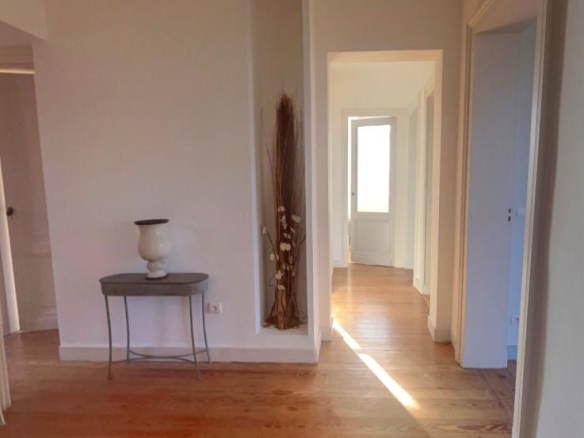 Interior of a renovated apartment in Arcachon, with a wooden hallway and light-colored walls.