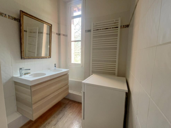 Renovated bathroom with vanity unit and bathtub, natural light